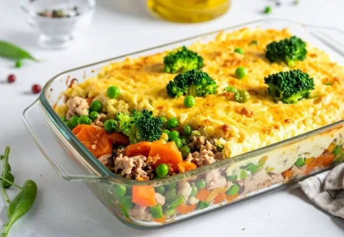 Healthy Tuna Casserole Recipe with colorful vegetables and a golden crust in a clear glass baking dish, set on a bright kitchen counter.