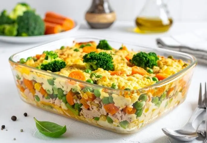 Cheesy tuna casserole with a golden, bubbling cheese crust and crispy breadcrumb topping, garnished with fresh parsley in a rustic ceramic dish.